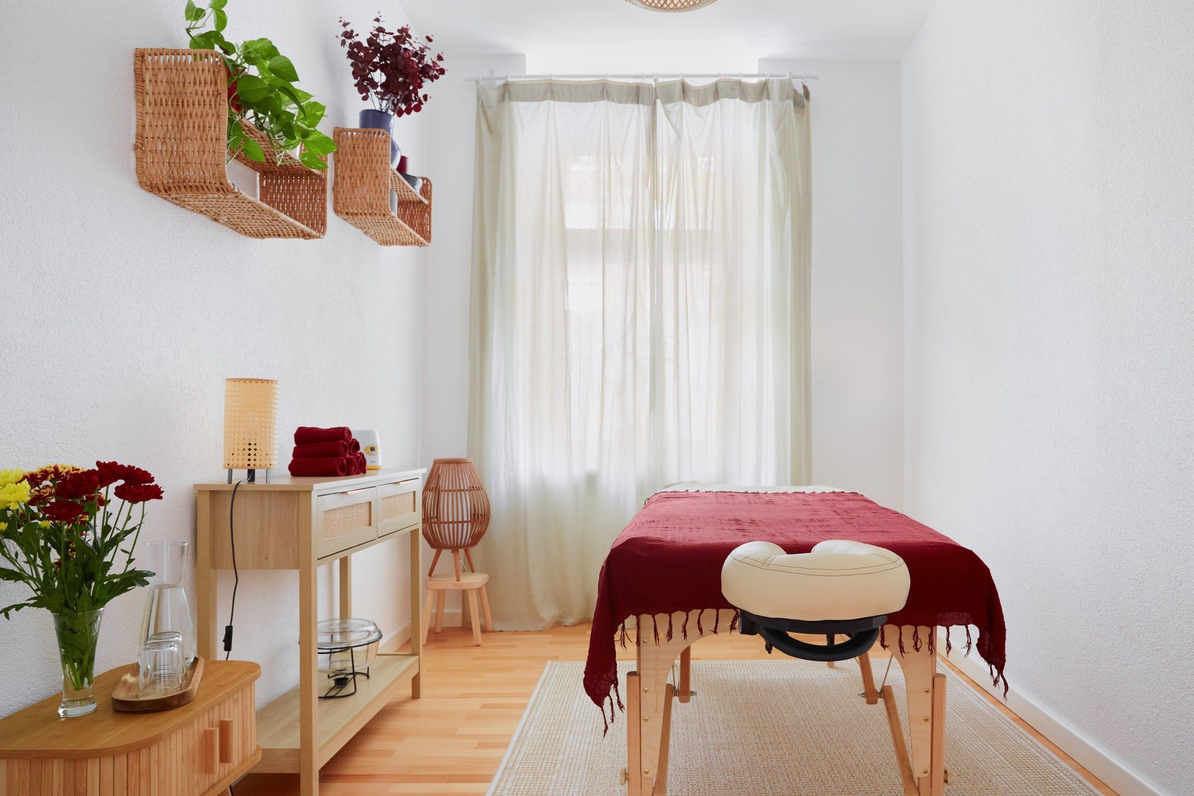Blick in den Cozy Room: Massageliege vor dem Fenster, Rattanregale mit Pflanzen